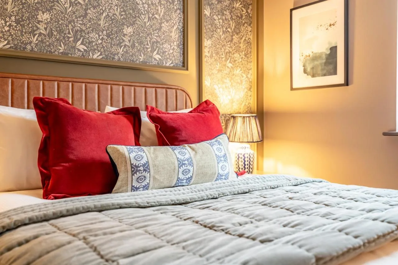 a bedroom with a bed with red pillows at The Falcon in York